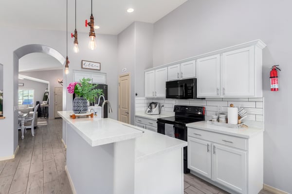Featuring quartz countertops, subway tile backsplash, white cabinetry, pendant lighting, and generous prep space, this bright kitchen blends timeless style with everyday functionality.