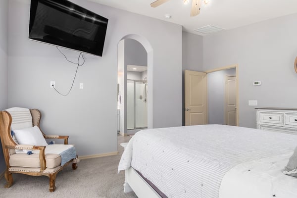 The spacious primary bedroom offers plush carpeting, a ceiling fan, neutral finishes, and convenient access to the ensuite bathroom. A peaceful retreat designed for comfort and relaxation.
