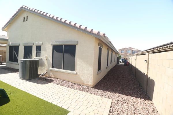 The home's side yard showcases easy-care desert landscaping, paver pathways, and convenient access around the property, providing attractive curb appeal with minimal maintenance in Buckeye.