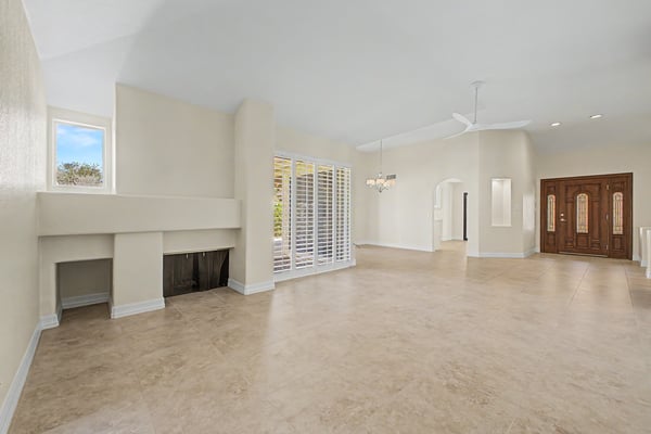 Relax beside the cozy fireplace in this expansive living room featuring plantation shutters, abundant natural light, and an open floor plan perfect for gatherings.