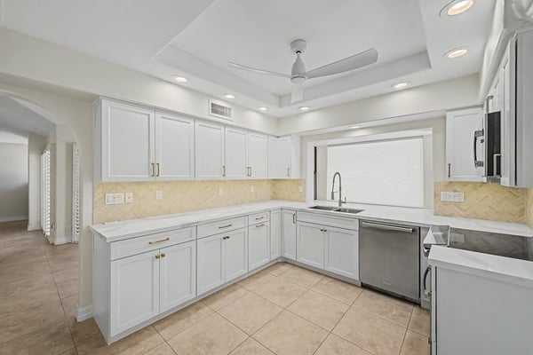 Thoughtfully updated kitchen featuring custom white cabinetry, elegant quartz counters, modern appliances, and an efficient layout offering abundant storage and workspace.
