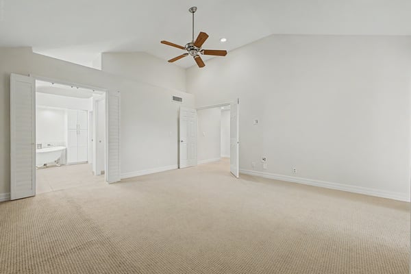 Bright primary suite with vaulted ceilings, soft carpeting, recessed lighting, and direct access to the remodeled en-suite bathroom. A peaceful space designed for comfort and relaxation.