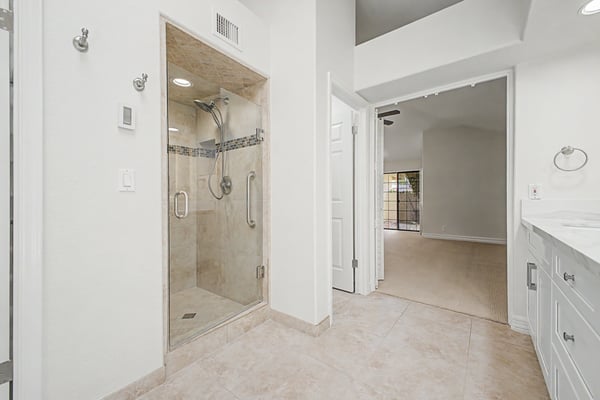 Beautifully renovated primary bathroom featuring a frameless glass walk-in shower, elegant tile surround, modern fixtures, and a clean, sophisticated design for everyday luxury.