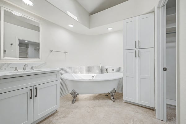 The elegant freestanding soaking tub serves as the centerpiece of this beautifully remodeled primary bathroom, complemented by custom storage, designer finishes, and a bright, airy atmosphere.