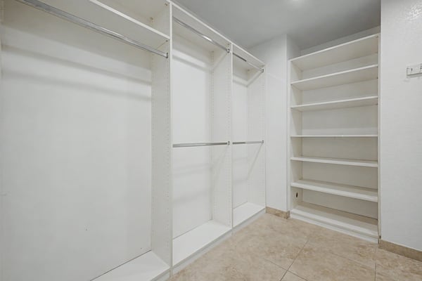 Large walk-in closet with custom built-in shelving, hanging space, and abundant storage designed to keep the primary suite organized and functional.