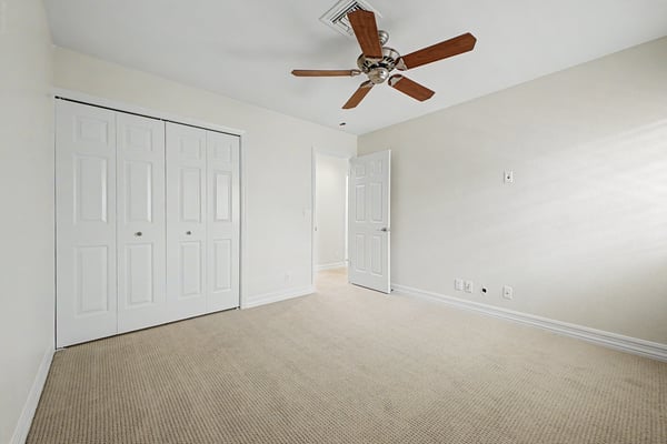 Spacious bedroom with generous closet storage, ceiling fan, plush carpeting, and neutral d cor, offering flexible living space for guests, hobbies, or remote work.