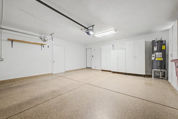 Finished two-car garage featuring durable epoxy flooring, extensive storage cabinets, and generous space for vehicles, recreational equipment, and workshop needs.