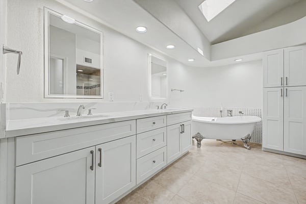 Spacious primary bathroom with dual sinks, custom cabinetry, quartz counters, and a luxurious freestanding soaking tub. Designed to provide both style and functionality in a relaxing setting.