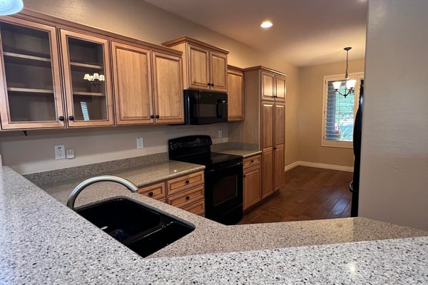 Spacious kitchen offering custom wood cabinetry, ample countertop space, breakfast bar seating, generous storage, and an open layout connecting seamlessly with the home's main living spaces.
