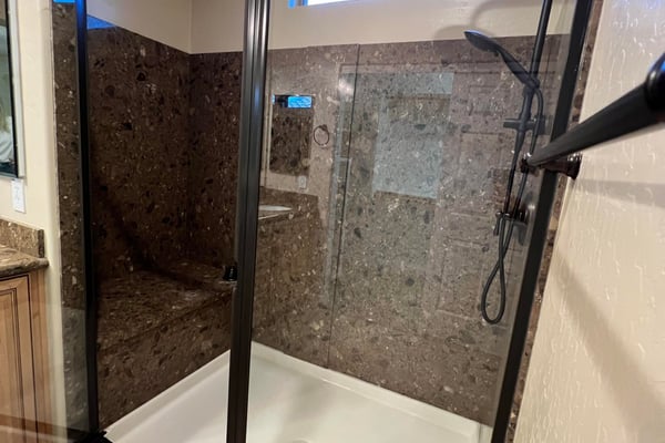 Luxurious walk-in shower with stylish tile surrounds, built-in bench seating, black framed glass enclosure, and upgraded shower fixtures creating a sophisticated spa-like experience.