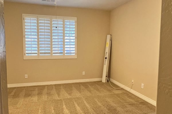 Inviting secondary bedroom featuring soft carpeting, plantation shutters, ceiling fan, and abundant natural light. Ideal as a guest suite, hobby room, or private office space.