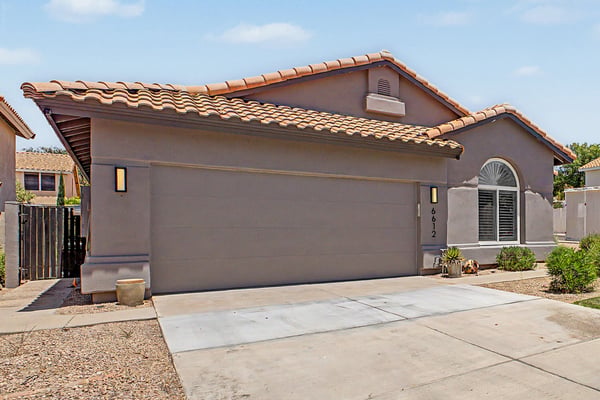 Inviting covered entry featuring a custom wood front door, architectural archway, and landscaped walkway. An impressive entrance that reflects the home's quality craftsmanship.