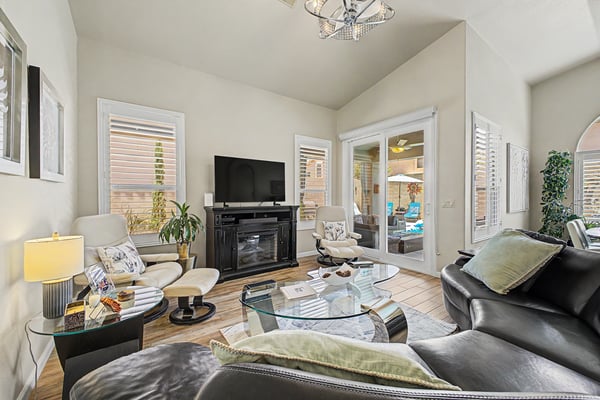 Spacious living room showcasing soaring ceilings, large windows, stylish flooring, and a cozy fireplace. The thoughtfully designed layout offers comfort and functionality throughout.