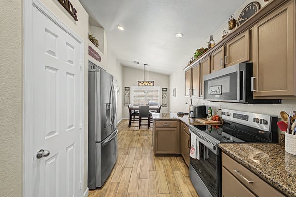 Bright kitchen overlooking the adjacent dining space, featuring granite countertops, stainless steel appliances, abundant cabinet storage, and durable tile flooring throughout.