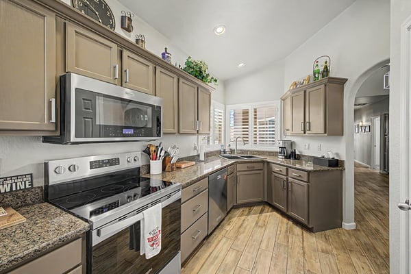 Spacious kitchen designed with granite countertops, quality stainless steel appliances, recessed lighting, generous workspace, and plantation shutters that enhance both style and functionality.