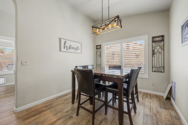 Comfortable dining area featuring modern lighting, plantation shutters, tile flooring, and plenty of natural light. An inviting space perfect for casual meals and everyday gatherings.