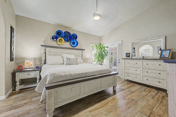 Large primary bedroom featuring vaulted ceilings, beautiful flooring, abundant natural light, and private access to the outdoor living space. Designed as a peaceful retreat at the end of the day.
