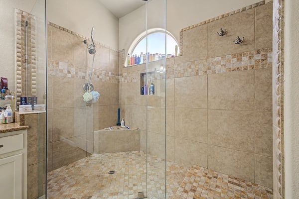 Elegant walk-in shower with a frameless glass enclosure, custom tile surround, decorative accents, and built-in shelving. A luxurious feature that adds comfort and sophistication to the primary bathroom.