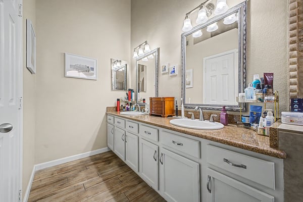 Elegant primary bathroom with dual sinks, expansive vanity, framed mirrors, generous storage, and bright lighting. A thoughtfully designed space that blends comfort and functionality.