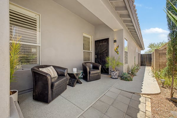 Charming covered side patio featuring comfortable seating, attractive desert landscaping, and secure gated access. This versatile outdoor space offers privacy and additional room to relax in this Mesa home.
