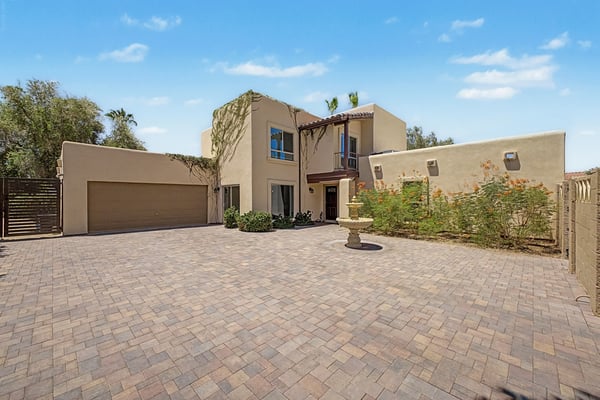 Welcome home through a gated courtyard featuring an expansive paver driveway, decorative fountain, and modern entry gates. This inviting exterior offers privacy, convenience, and impressive curb appeal in Scottsdale.