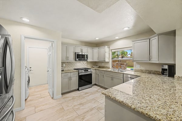 The remodeled kitchen showcases granite countertops, stainless steel appliances, recessed lighting, and generous cabinet storage. The open layout offers both style and functionality for modern Scottsdale living.