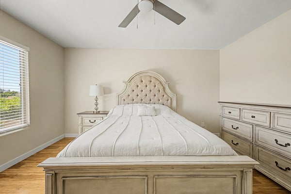 Spacious bedroom offering warm wood-look flooring, abundant natural light, ceiling fan, and flexible living space. A comfortable room designed for everyday functionality.