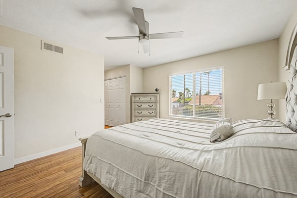 Comfortable bedroom with large windows, wood-look flooring, ceiling fan, and ample space for furnishings. Bright natural light enhances the clean, modern feel of this Scottsdale home.