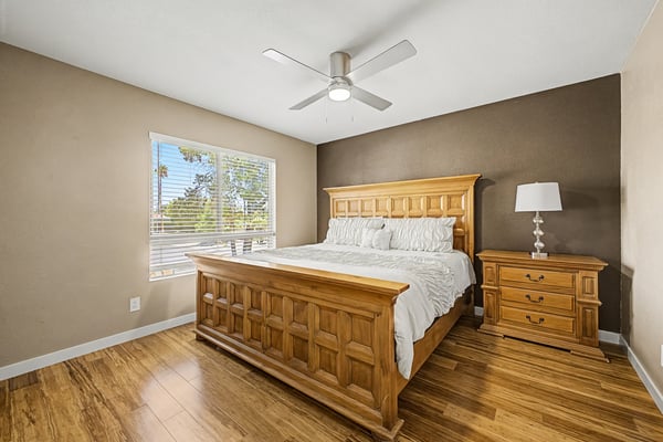Spacious guest bedroom featuring attractive wood-look flooring, ceiling fan, neutral finishes, and a large window for natural light. A welcoming space offering comfort and flexibility in this Scottsdale property.