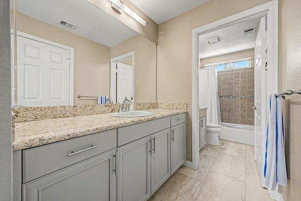 Updated guest bathroom showcasing granite countertops, modern gray cabinetry, upgraded fixtures, and tile flooring. A stylish bathroom designed for everyday comfort and convenience.