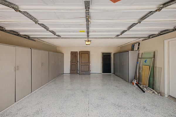 Finished garage with epoxy-coated flooring, abundant built-in storage cabinets, and generous room for vehicles, tools, and extra storage. A practical feature that complements this Scottsdale home.