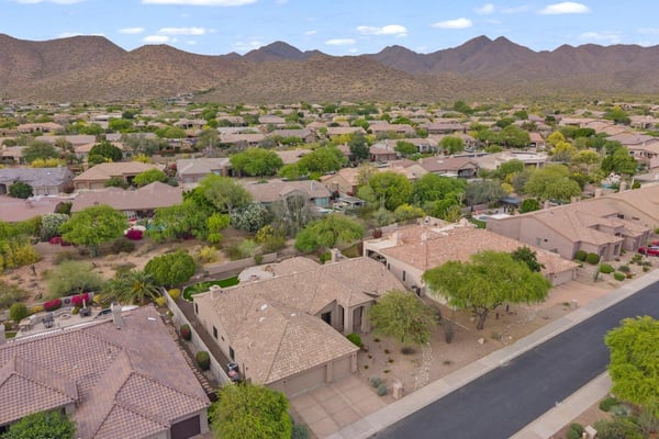 Elevated aerial showcasing the surrounding Scottsdale neighborhood, scenic mountain vistas, and the home's excellent location among beautifully maintained residences.