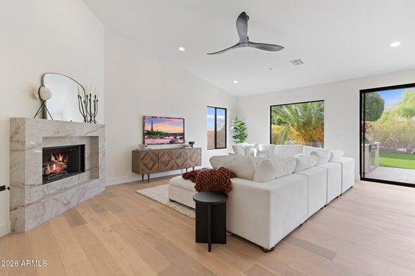 Elegant family room highlighted by a modern fireplace, soaring ceilings, oversized windows, and beautiful backyard views. Designed for comfortable living and effortless entertaining.