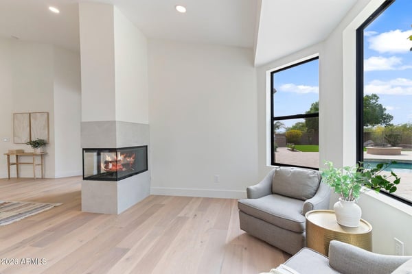 Comfortable sitting space adjacent to the primary bedroom featuring a sleek fireplace, oversized windows, and tranquil outdoor views. Perfect for reading, relaxing, or enjoying quiet mornings.