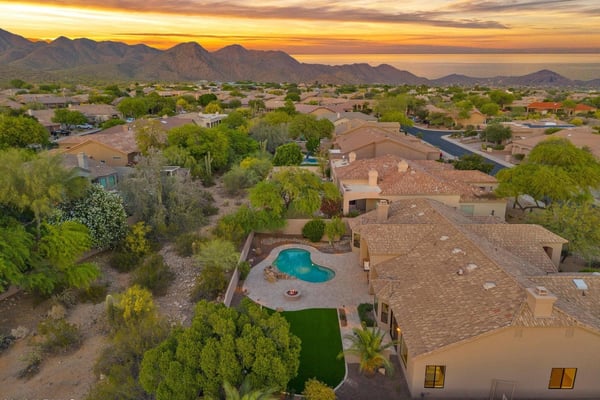 Elevated aerial highlighting the private backyard retreat, resort-style pool, expansive entertaining patio, and bordering desert wash. This Scottsdale property offers peaceful outdoor living and scenic natural surroundings.
