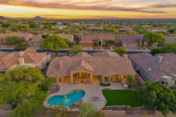 Aerial perspective showcasing the custom pool, fire pit, covered patio, artificial turf, and spacious backyard designed for entertaining. Enjoy resort-inspired living in this Scottsdale home.