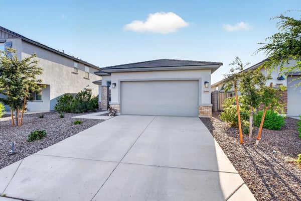 Charming front exterior showcases modern architecture, stone accents, desert landscaping, and a spacious attached garage, delivering outstanding curb appeal in Surprise.