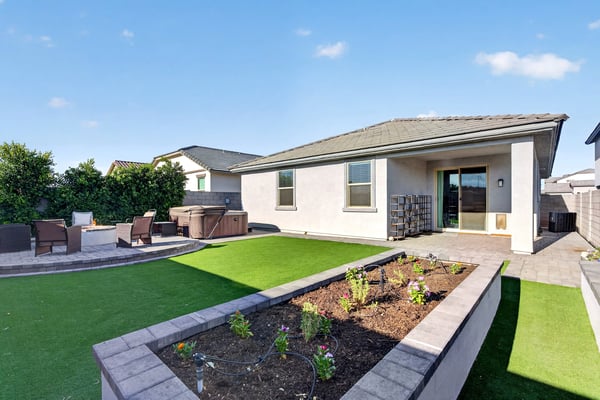Professionally finished with synthetic grass, raised planter beds, paver patios, and covered outdoor living, this backyard provides the perfect blend of beauty, comfort, and low-maintenance landscaping.