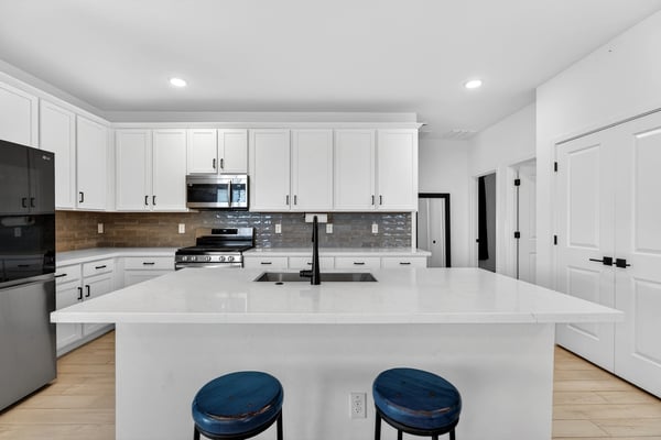 The expansive kitchen island provides casual seating, extra storage, quartz countertops, and an ideal gathering place while maintaining an open connection to the home's living areas.