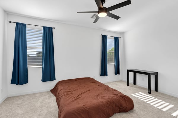 This spacious primary suite offers plush carpet, multiple windows, ceiling fan, and a relaxing atmosphere designed to provide comfort and privacy after a busy day.