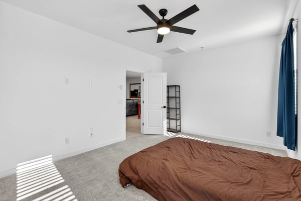 Relax in this inviting primary suite featuring plush carpeting, soaring ceilings, ceiling fan, abundant natural light, and easy access to the ensuite bathroom and walk-in closet.