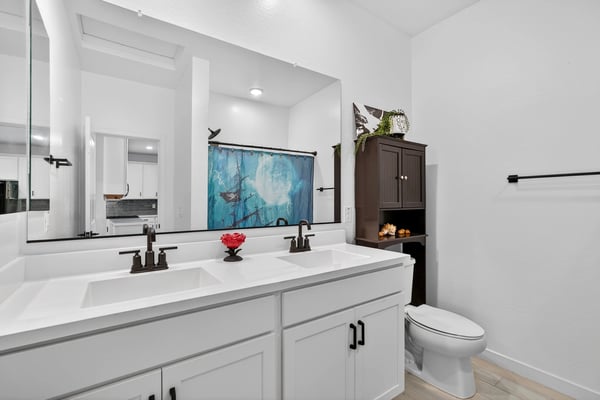 Stylish hall bathroom featuring dual vanities, quartz countertops, modern cabinetry, black fixtures, and plenty of storage for convenient everyday use.