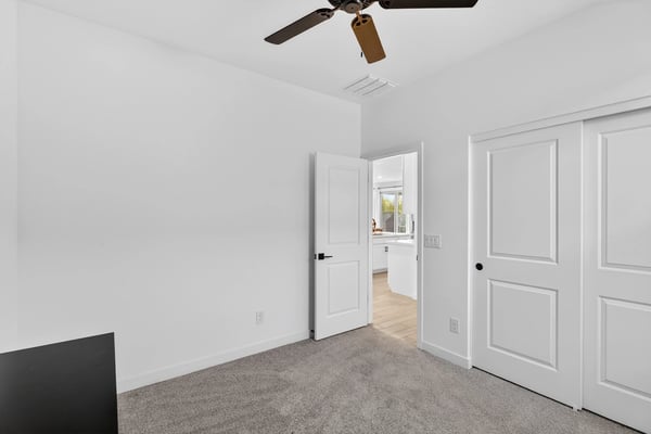 This spacious bedroom offers neutral finishes, soft carpeting, generous closet storage, and flexible living space perfect for family, guests, or a home office.