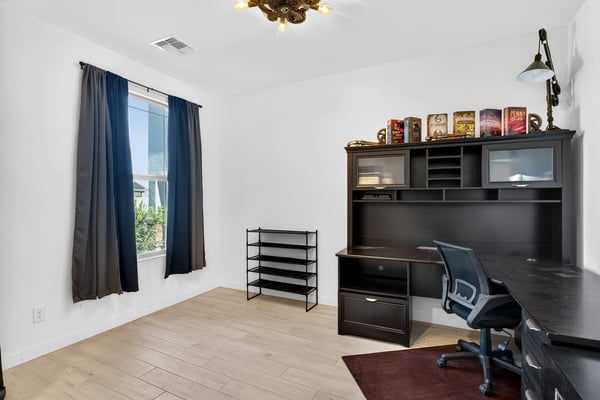 A spacious office with large windows, wood-look tile flooring, and ample room for desks or creative projects offers excellent flexibility for today's lifestyle in Surprise.