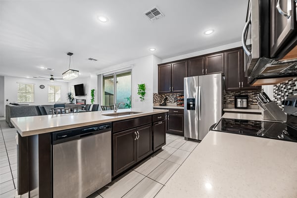 Open-concept kitchen featuring quartz countertops, stainless steel appliances, a large center island, and abundant cabinetry. Pe