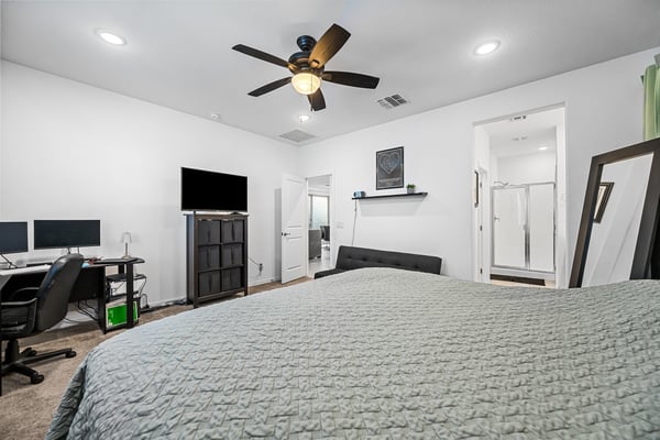 Bright owner's suite featuring plush carpet, ceiling fan, generous layout, and flexible space for additional seating or a workspace. A welcoming retreat within this Goodyear home.