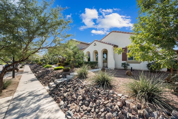 Welcoming front exterior showcasing desert landscaping, covered front porch, and timeless architectural styling. Beautifully maintained and ready for its next owner in Goodyear.