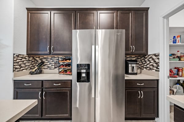 Modern kitchen offering quartz countertops, stainless steel appliances, rich cabinetry, and an oversized walk-in pantry. A beautiful blend of style, storage, and everyday functionality.