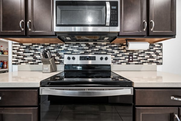 Detailed view of the upgraded kitchen featuring stainless steel appliances, quartz counters, decorative backsplash, and ample cabinetry. Designed for both beauty and performance in this move-in ready Goodyear home.