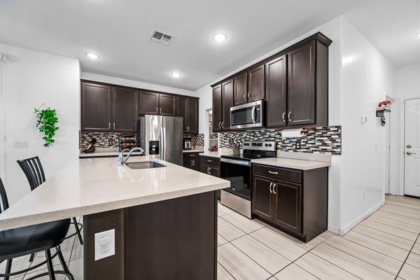 Another view of the beautifully designed kitchen featuring quartz countertops, stainless steel appliances, decorative backsplash, and abundant cabinet storage for everyday convenience.